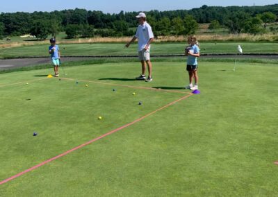 Golf coach helping children’s golf camp attendees